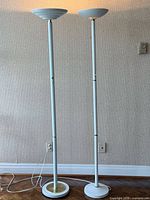 Full view of both white torchiere lamps standing side by side
