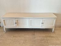 Front view of white painted low credenza with four doors and tapered legs