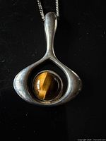 Front view of sterling silver pendant with tiger eye cabochon