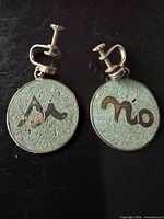 Front view of both earrings showing “Sí” and “No” text and screw-back fittings