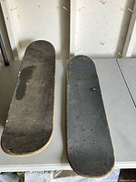 Two skateboard decks top view showing grip tape wear