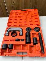 Ball joint press kit in open orange case showing C-frame, forcing screw and seven adapters; empty slots visible indicating missing pieces