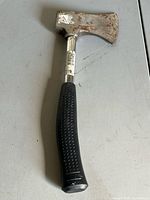 Hatchet front view showing rusted steel head, chrome shaft, black textured grip