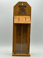 Full front view of wooden cuss bank showing poem, coin slots, viewing window