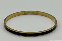 Full view of the bangle showing black enamel exterior and gold-tone edges
