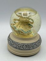 Front view of Sankyo snow globe showing angel figure, glitter, and decorative base