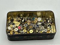 tin open showing assorted buttons filling interior