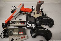 Group shot showing NES Zapper, three NES controllers, Sup handheld, two Genesis controllers, Recoton joystick