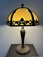 Lamp illuminated, showing slag glass panels and metal overlay