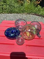 Group of five assorted glass hanging balls on red surface outdoors