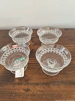 Four pressed glass nappies on wooden surface