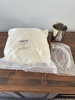 Bag of white soy wax flakes, stainless steel jug, bundle of candle wicks