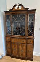 Front view of Georgian style burl walnut hutch showing glass doors, drawers, cabinets, and pediment finial