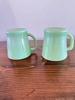 Two jadeite mugs upside down showing color and shape