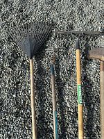 Four tools close-up: plastic leaf rake, stirrup hoe, bow rake, half-moon edger
