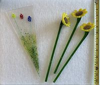 Group shot of three daffodil glass stems and triangular plate with measuring tape