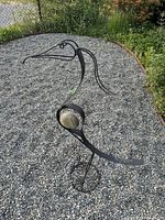 Full view of iron heron sculpture on gravel surface