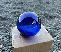 Side view of cobalt blue glass float on cardboard box