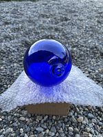 Full view of cobalt blue glass float showing pontil seal on bubble wrap