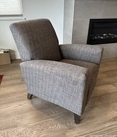 Front side view of grey fabric recliner showing overall design and legs