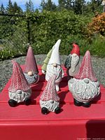 Front view of six plaster gnomes on red table