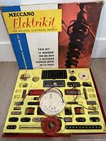 Open Meccano Elektrikit box showing tray with electrical parts and box lid graphics