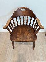 front angled view of oak captain’s chair showing seat, spindles and backrest
