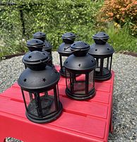 Front angled view of six matching black lanterns