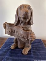 Front view of cast iron dog holding welcome sign