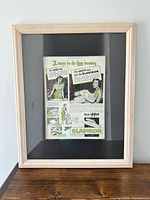 Framed magazine advertisement under glass