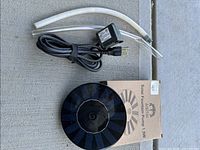 Solar fountain pump front, vinyl tubing and power adapter visible with box