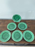 Six matching green leaf-pattern plates displayed face up