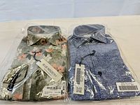 Front view of both packaged shirts displaying brand tags, colors and size labels