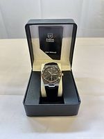 Watch in open Ernest Ferdinand box showing dial, strap, and manual