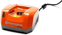 Top angled view of orange Husqvarna QC330 charger with attached power cord visible