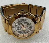 Front view showing gold skeleton dial and bracelet