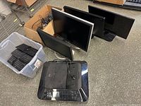 Overview of four monitors, tote of keyboards, box of cables and Canon printer