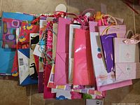 Stack of assorted colourful paper gift bags showing front designs and varied handle styles