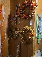 Pegboard wall showing two wreaths, four wood signs and a leaf-star garland