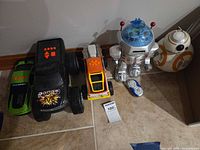 Group shot of five toys: green sports car, black Dodge truck, yellow pickup, silver robot, BB-8 droid