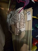 Folded patterned curtain panel on hanger showing grommet header and woven fabric