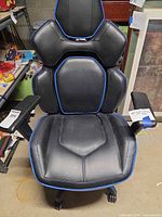 Front view showing black faux leather chair with blue trim and segmented backrest