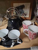 Group view of kettle, four mugs, tray and framed print on easel