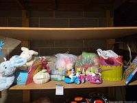 Shelf view of plush bunnies, baskets, bubbles, figurines, egg container, books