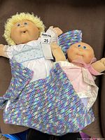 Front view of two dolls with clothing and blanket visible