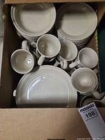 Top view of boxed dinnerware showing mugs, bowls, plates