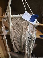 Overall view of macramé hanger, dowel and portion of crochet doily