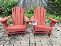Front view of both red wooden Adirondack chairs on patio