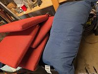 Stacked red and blue outdoor cushions on workbench