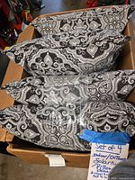 Box containing four identical black and white paisley 20x20 in throw pillows